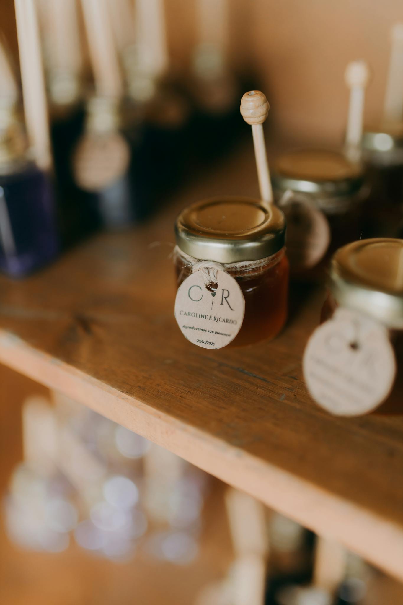 Close-up of artisanal honey jars with dipper sticks on a rustic wooden shelf.