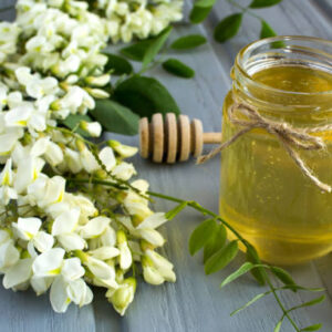 Honey and acacia flowers on the gray wooden background. close up.