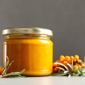 Delicious sea buckthorn jam and fresh berries on grey table. space for text