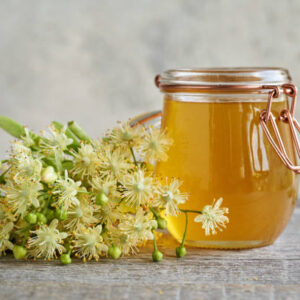 Fresh linden flowers with a jar of honey on a table