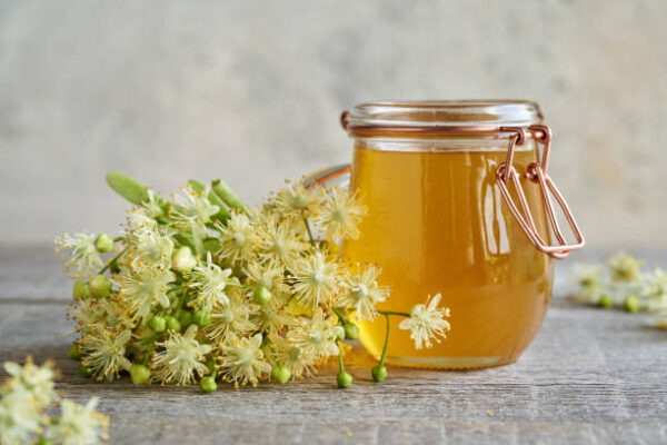 Fresh linden flowers with a jar of honey on a table