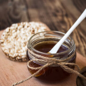Jar of honey with rice cookies on wooden background