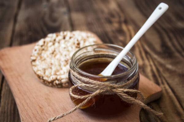 Jar of honey with rice cookies on wooden background